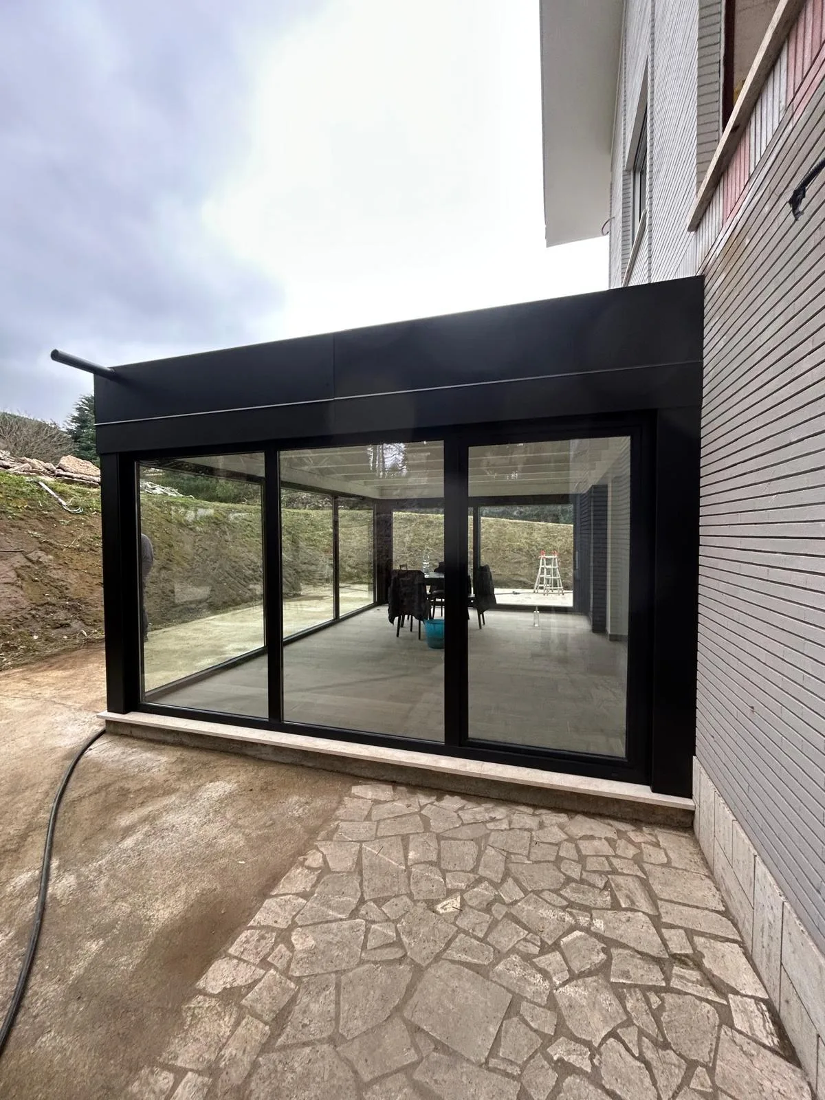 Veranda in alluminio nero con vetrate scorrevoli a chiusura di un patio