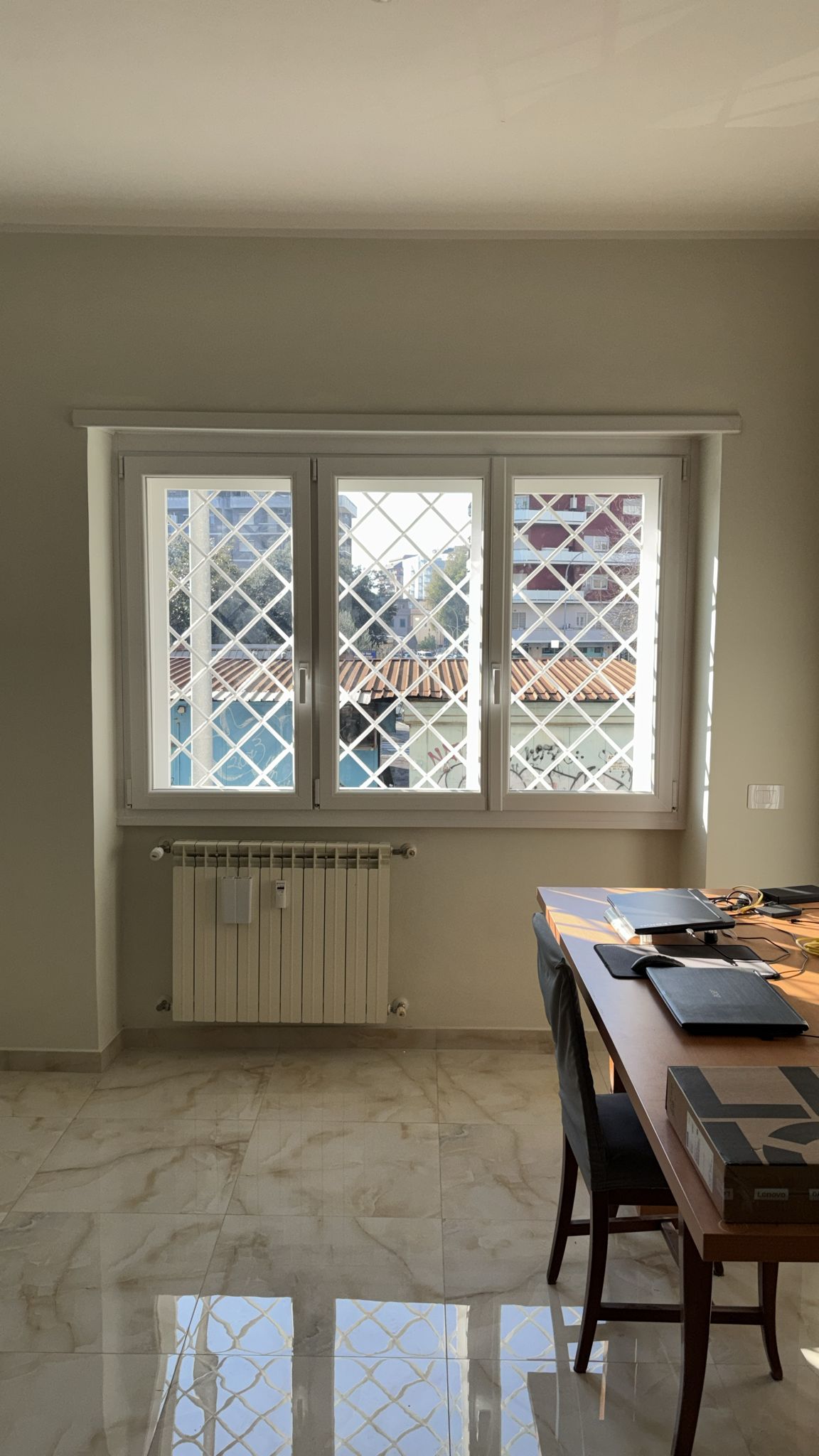 Finestra in PVC bianca con inferriata a rombi in una sala da pranzo